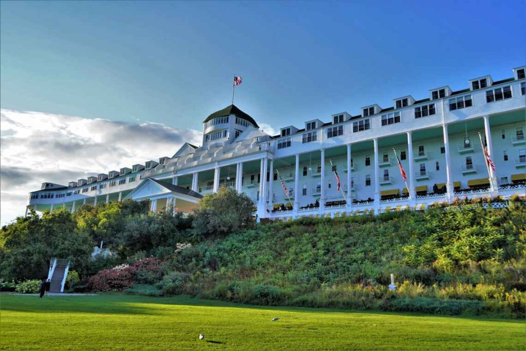 wide white front of the grand hotel on mackinac island in michigan with green lawn and landscaping