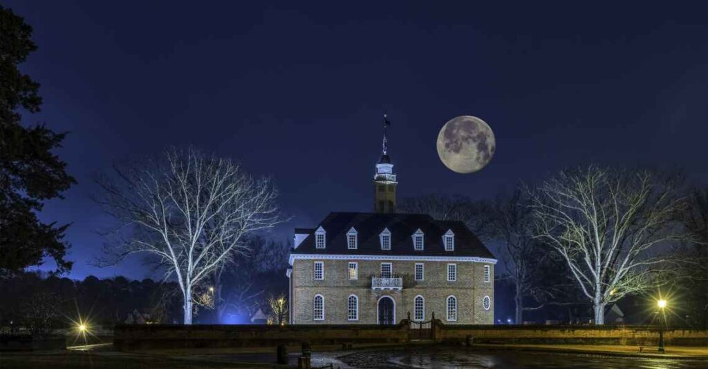historic stone building in williamsburg virginia at night with large moon overhead