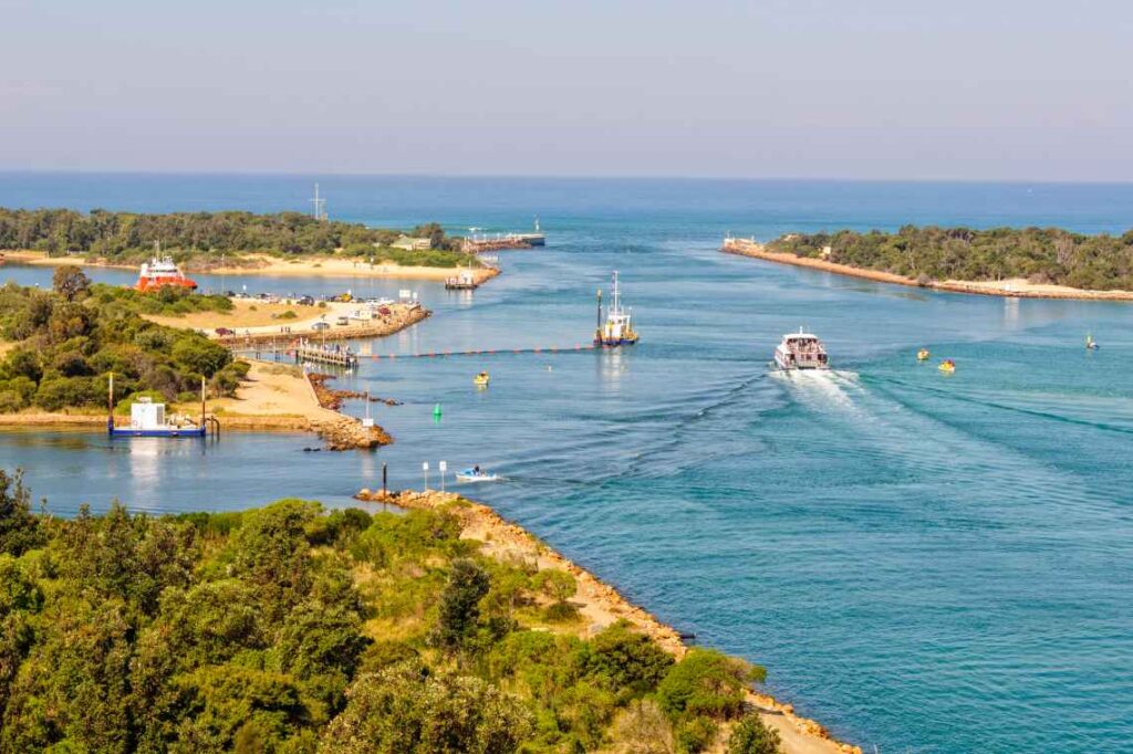 ships passing between small islands covered in trees with turquoise blue water at lakes entrance, australia