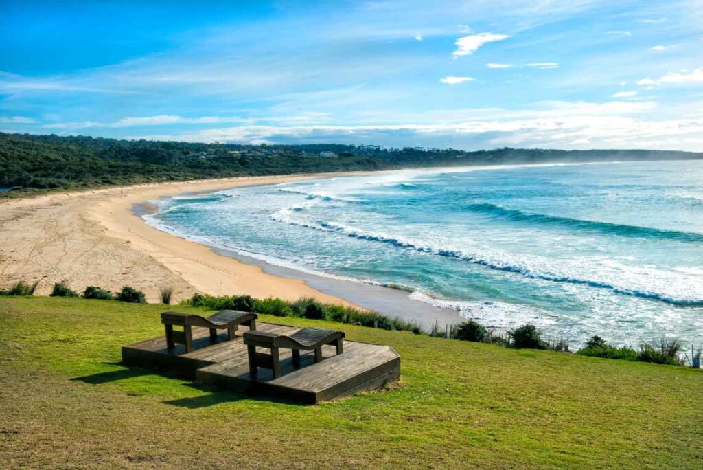 two wooden chairs on a wooden platform at short point beach near merimbula with turquoise water