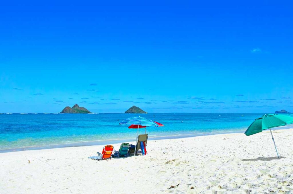 white sand lanikai beach with turquoise water and beach umbrellas and beach chairs