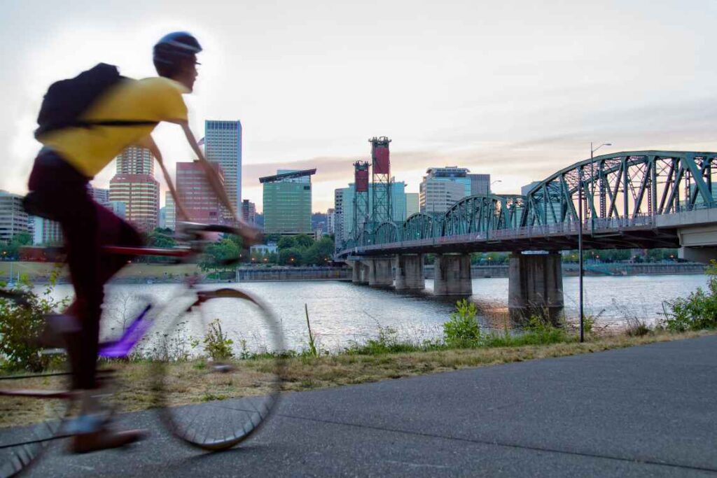 blurred man riding a bike on a bike path across the river from downtown portland