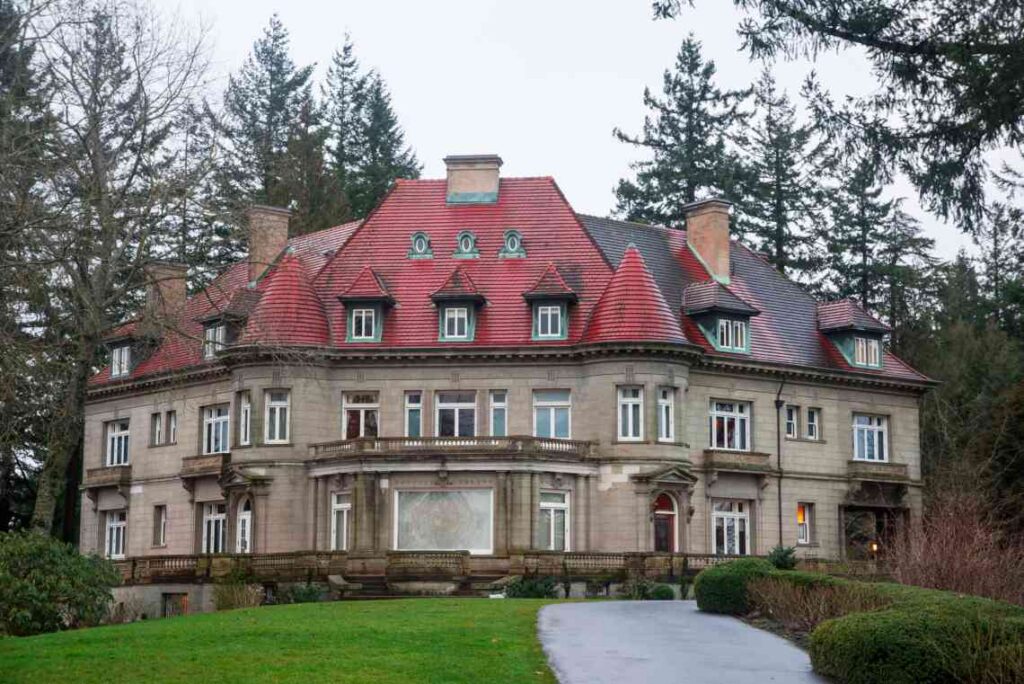 large stone mansion with red roof and 2 turrets