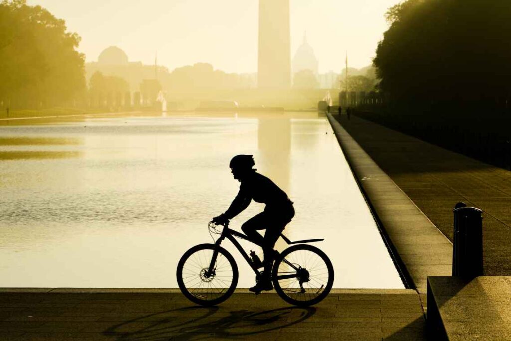 a man wearing a helmet biking on the national mall in washington dc at sunrise