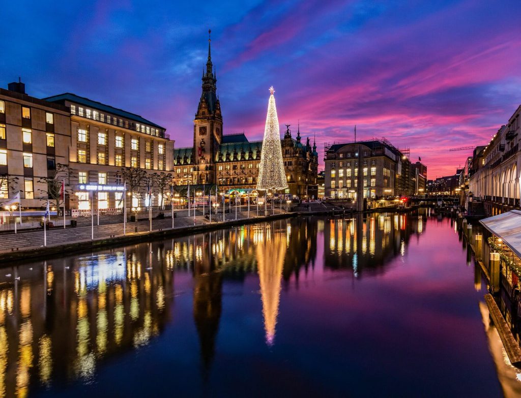 purple sky above Hamburg christmas market with alster river and christmas tree lit with white lights