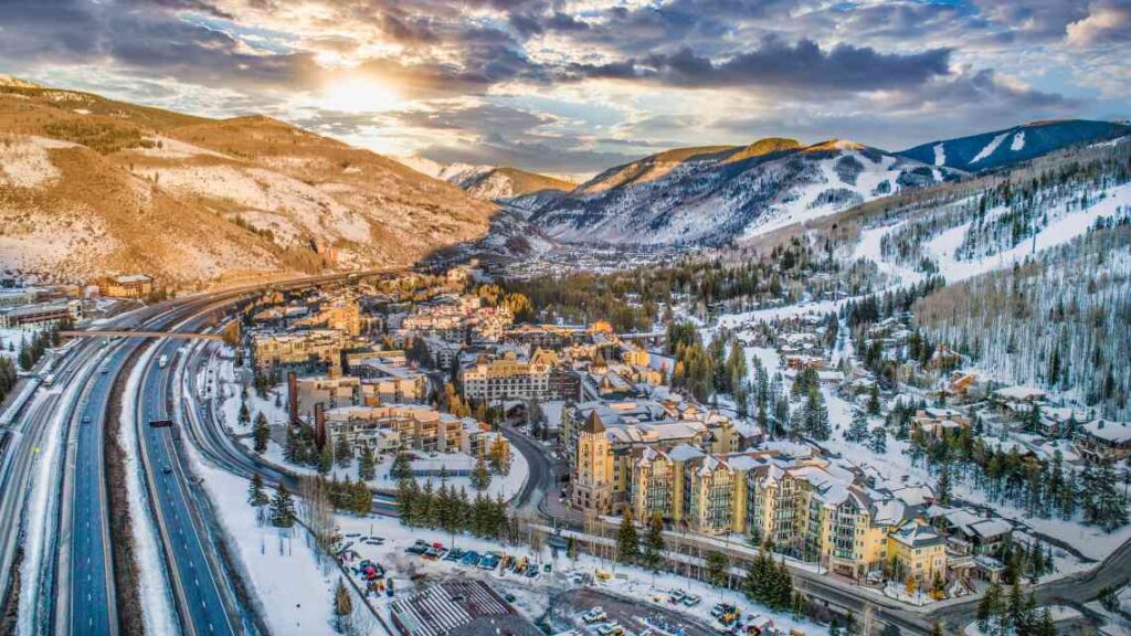 snow covered vail colorado from above with interstate road on the left and mountains with ski runs behind