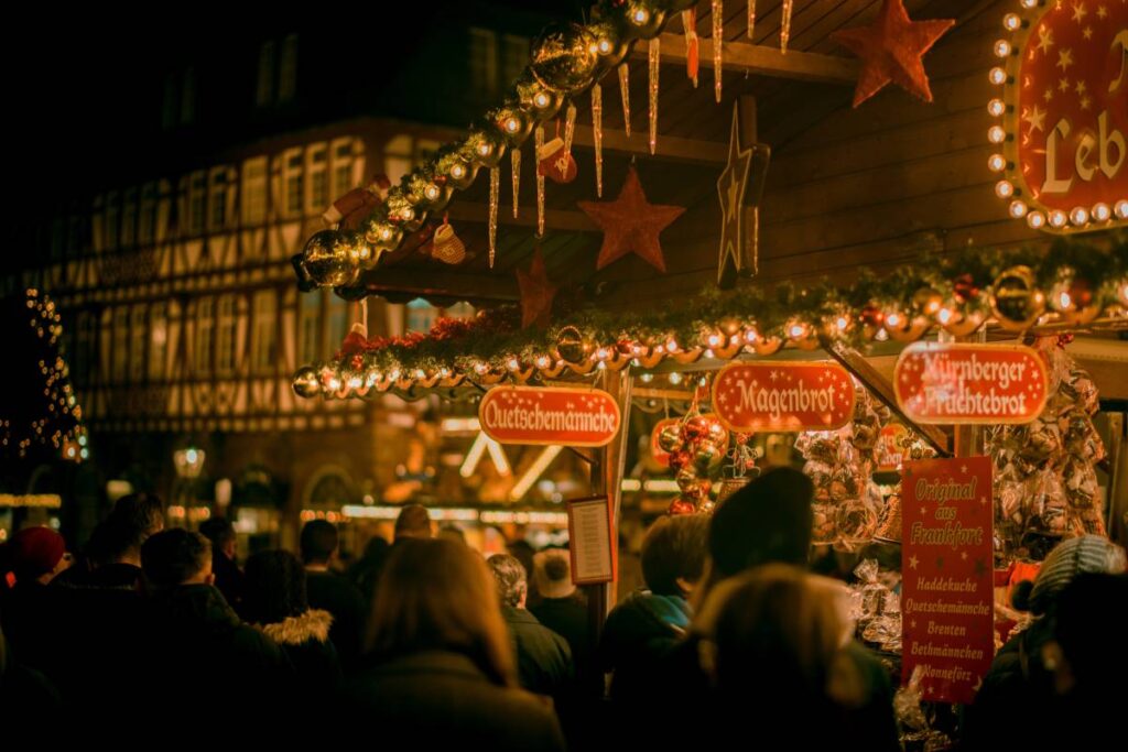 close up of christmas market stand hung with icicles and crowds of people around