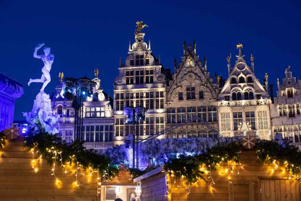 old buildings in antwerp, belgium, with the tops of christmas market stalls in the foreground