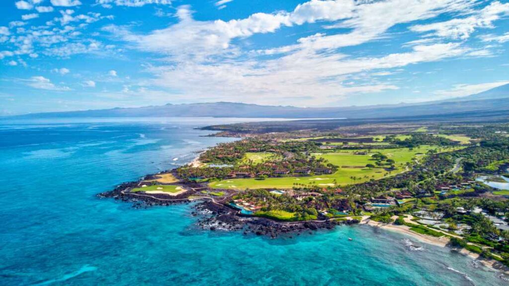 overhead of the south kohala coast in hawaii with lush green grass and blue waters