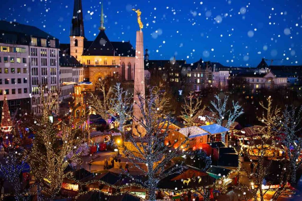 overhead shot of christmas market in luxembourg at night with snow falling