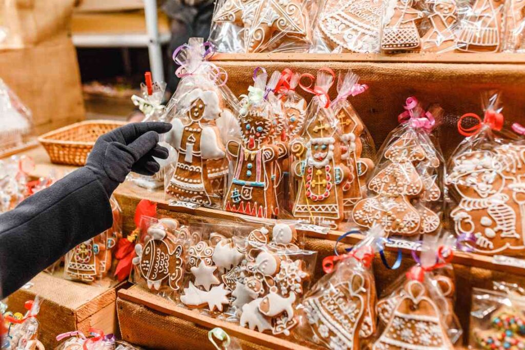 gloved hand reaching for decorated gingerbread in clear packaging
