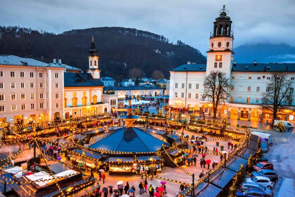 plaza with christmas market in salzburg, austria with mountains in the background