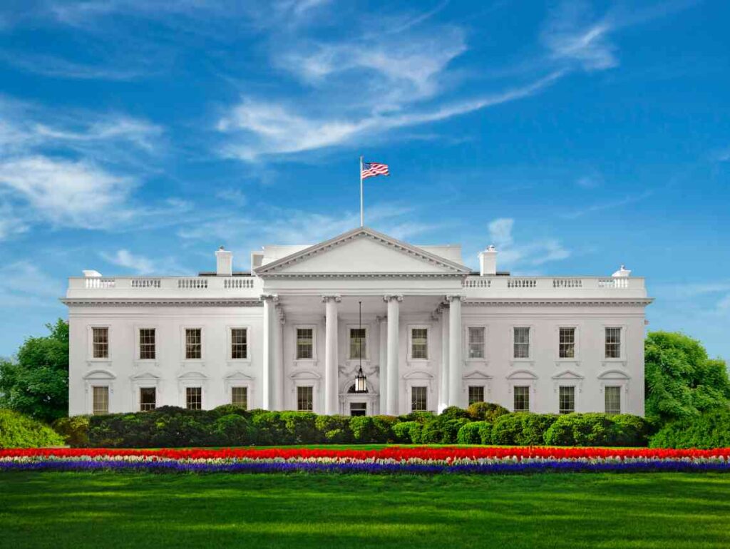us white house in front of blue sky and green lawn