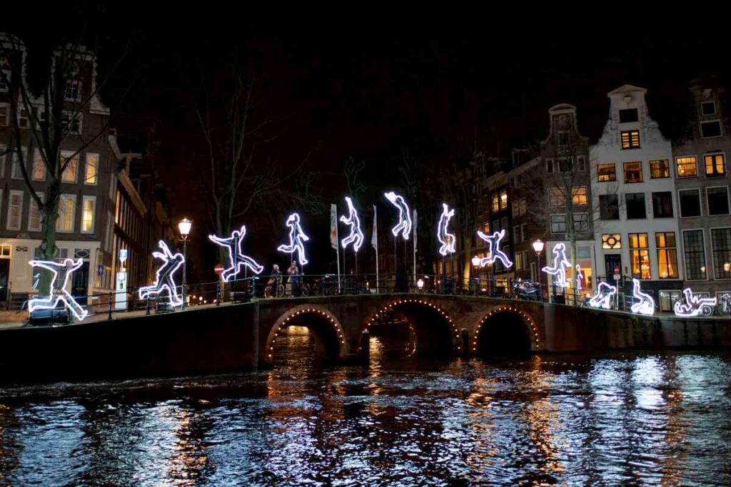 light installation of a person jumping and falling while going over a stone bridge as part of the amsterdam light festival