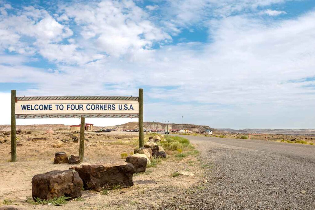 wooden sign saying Welcome to Four Corners U.S.A. on a gravel road in the arizona desert