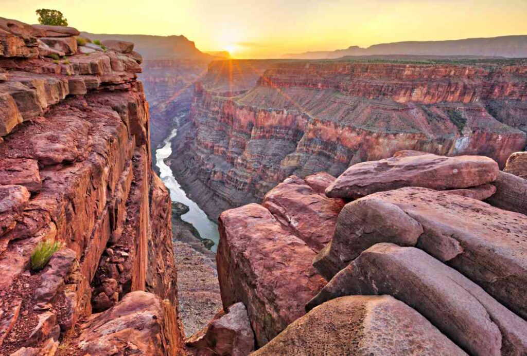 a view over the red rocks of the grand canyon with a river below at sunset from the arizona side