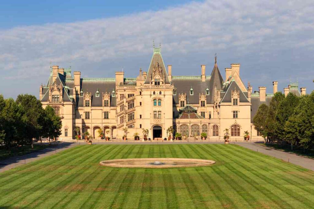 outside of large biltmore estate in north carolina with stone exterior and black and green roof with large green lawn