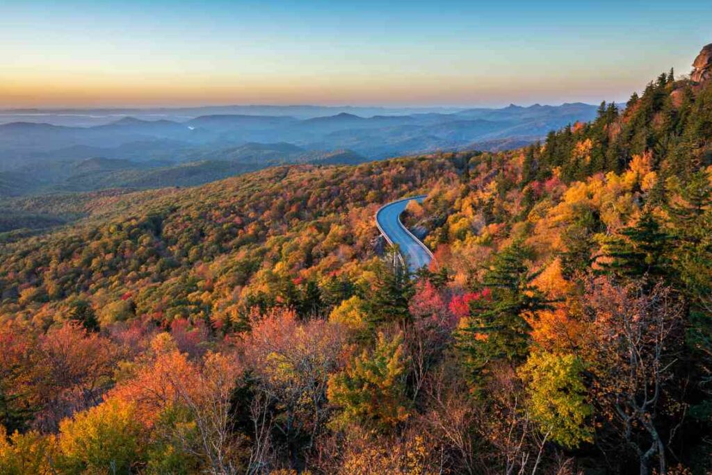 elevated blue ridge parkway winding along a tree-covered mountain with fall colors