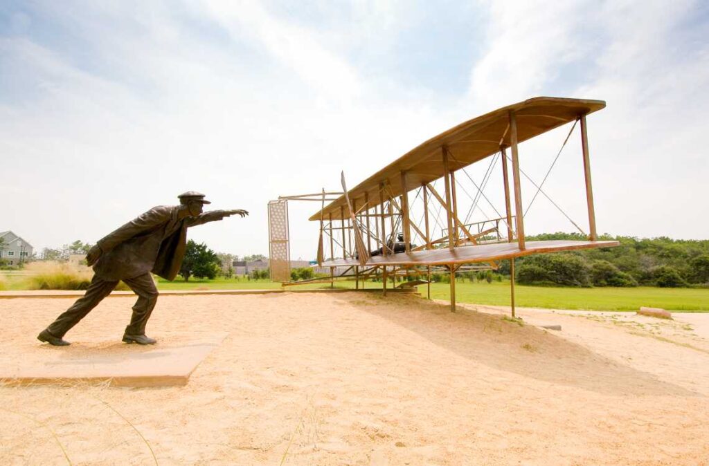bronze statue of a man with an airplane on a sanddune at the wright brothers memorial outside kitty hawk, nc
