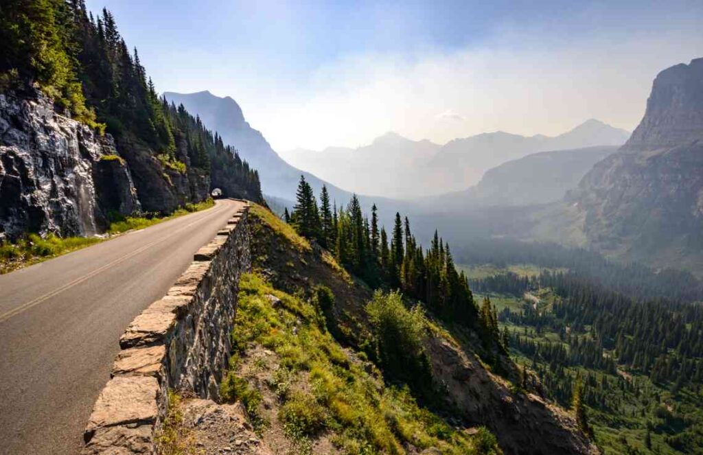 two lane going to the sun road in glacier national park in montana overlooking a valley with mountains on a sunny day
