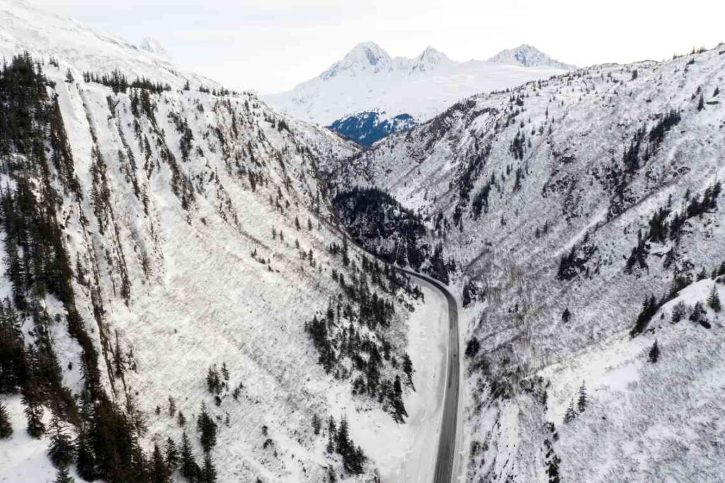 drone shot of the richardson highway near valdez in winter with snow covered mountains rising on either side