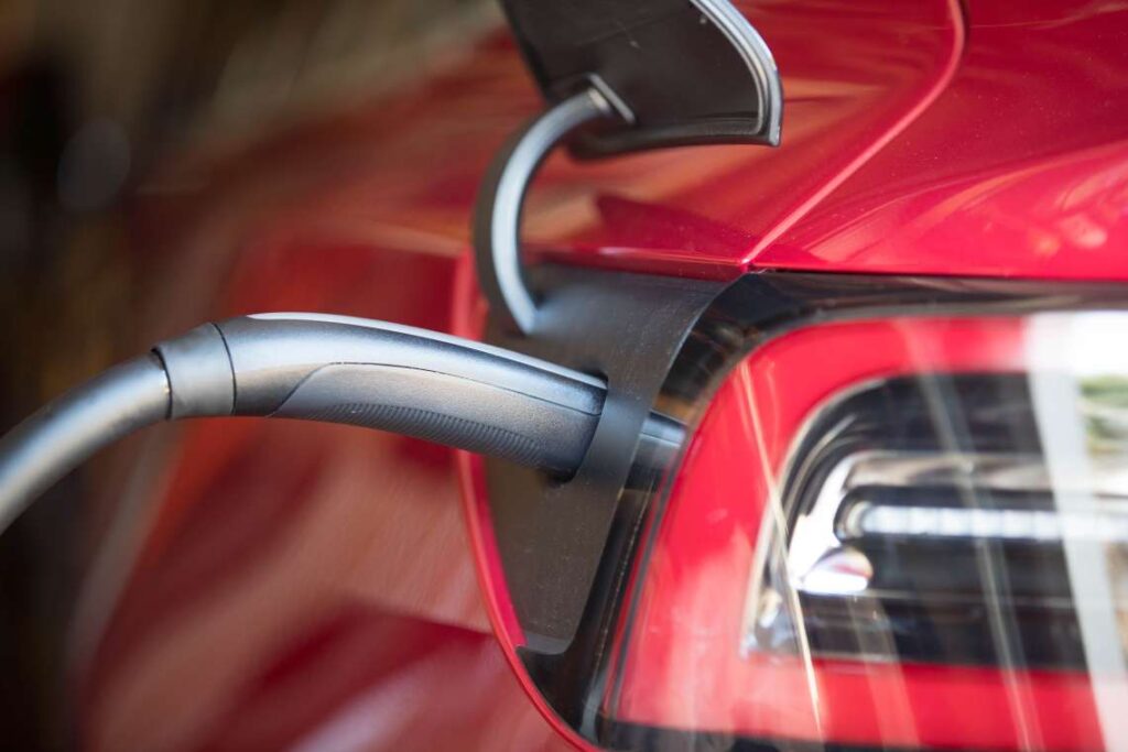 close-up do cabo de carregamento conectado a um carro elétrico Tesla vermelho