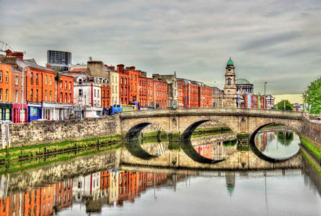 view of the stone mellows bridge over a river with cloudy skies in dublin, ireland
