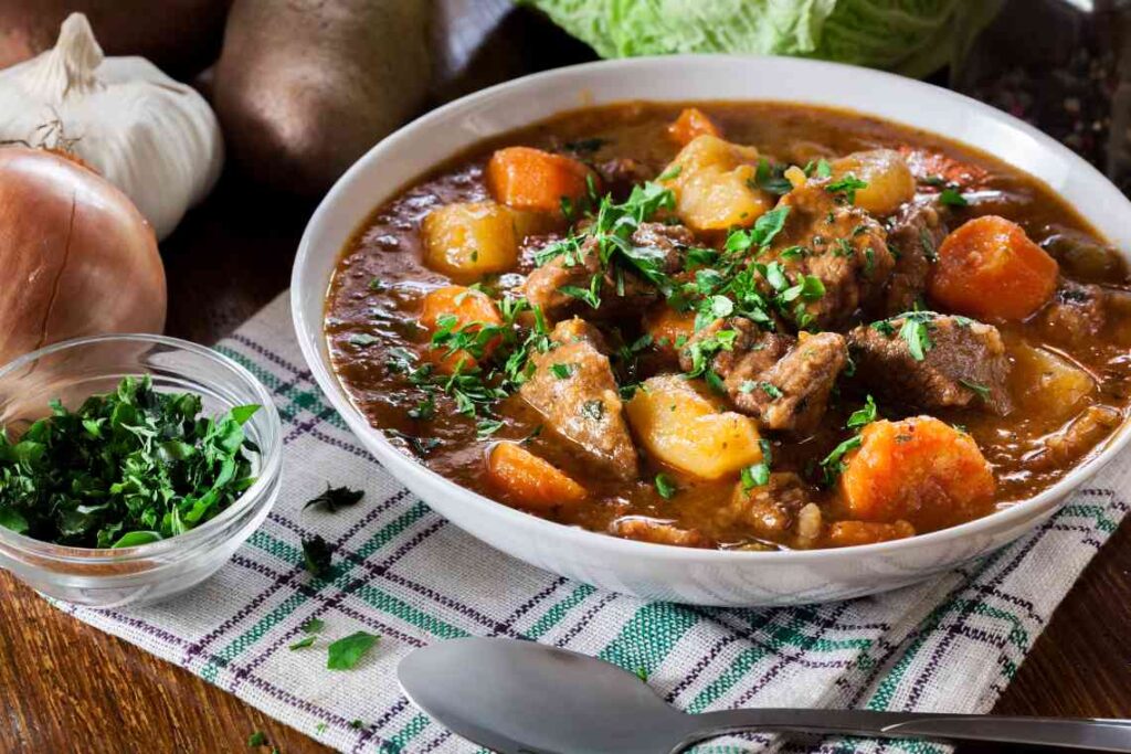 white bowl of irish beef stew with carrots and potatoes