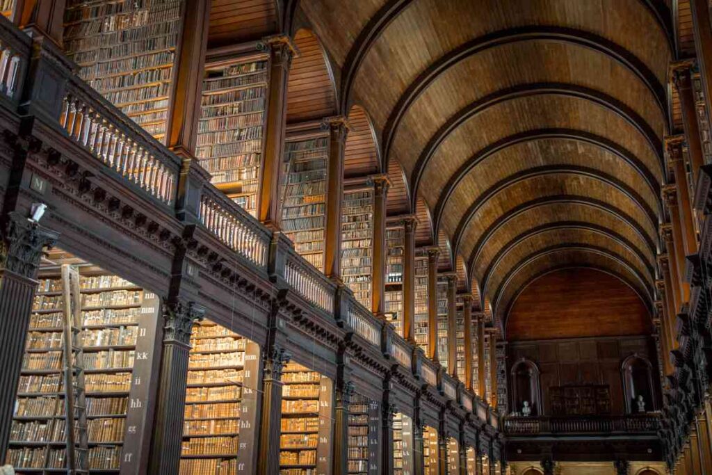 long rows of books in old wooden library at trinity college in dublin