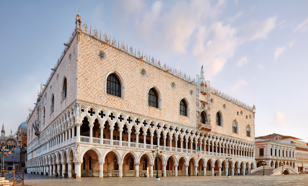 outside of the doge's palace in venice with intricate stone design in brown and white with white stone portico