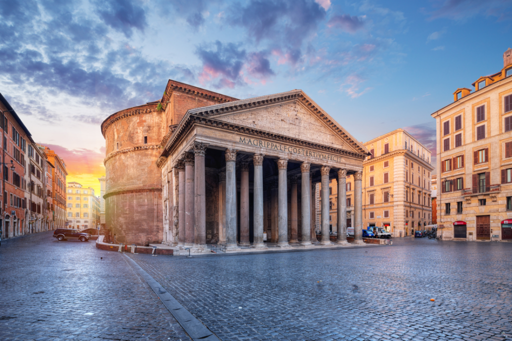 front of ancient stone building the pantheon in rome with colums and cobblestone plaza in front of it