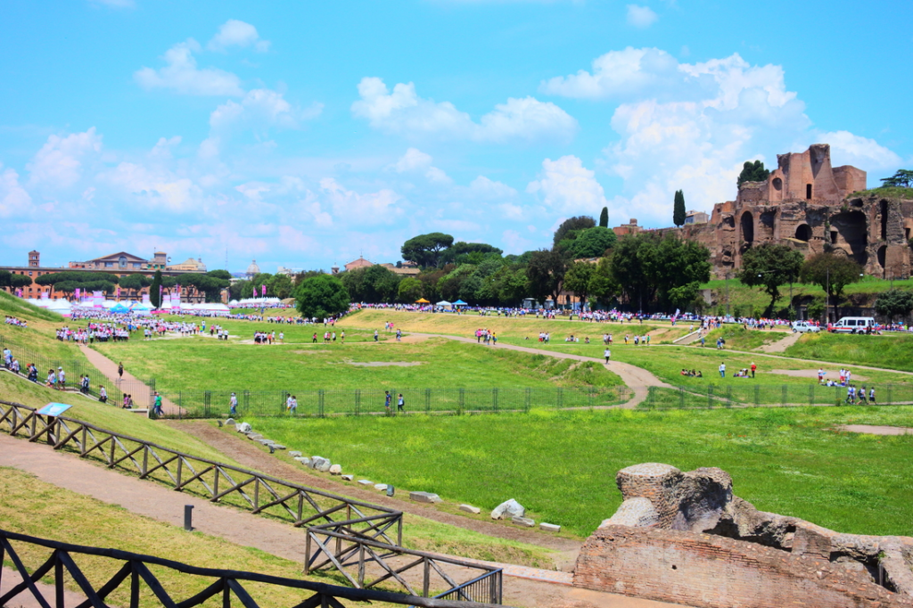 ruins of ancient roman chariot racing stadium circus maximus with green grass and people walking around