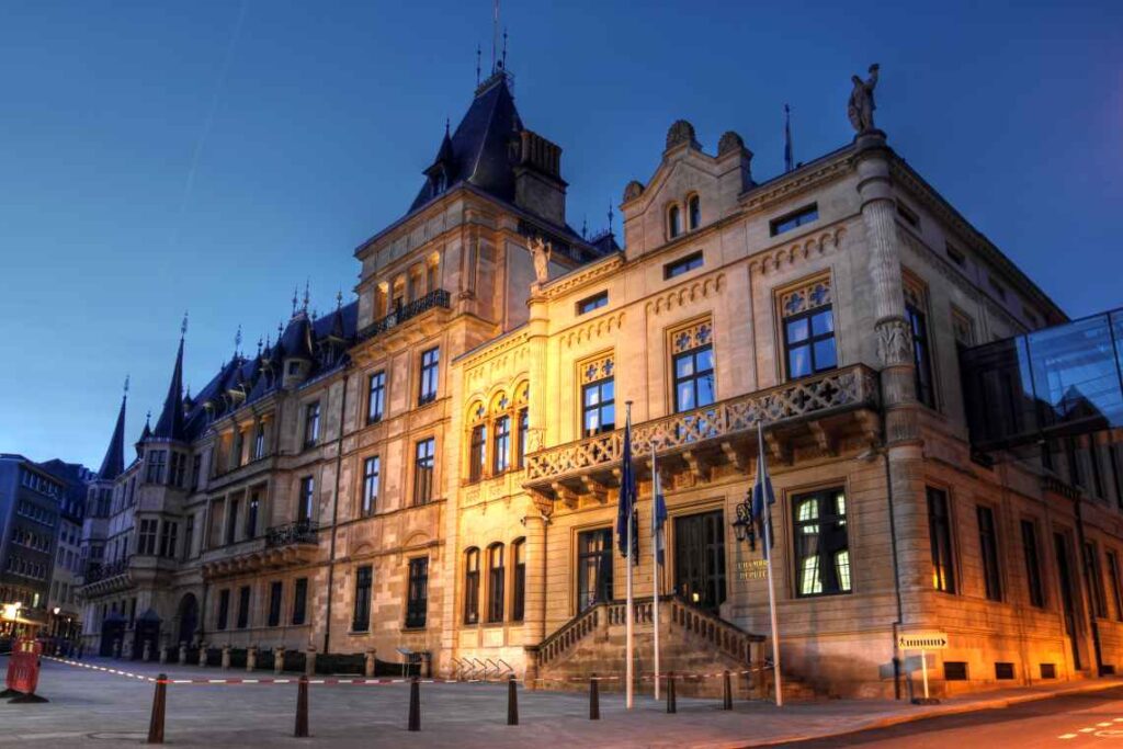 detailed stone exterior of palais grand ducal in luxembourg at night with light shining on it