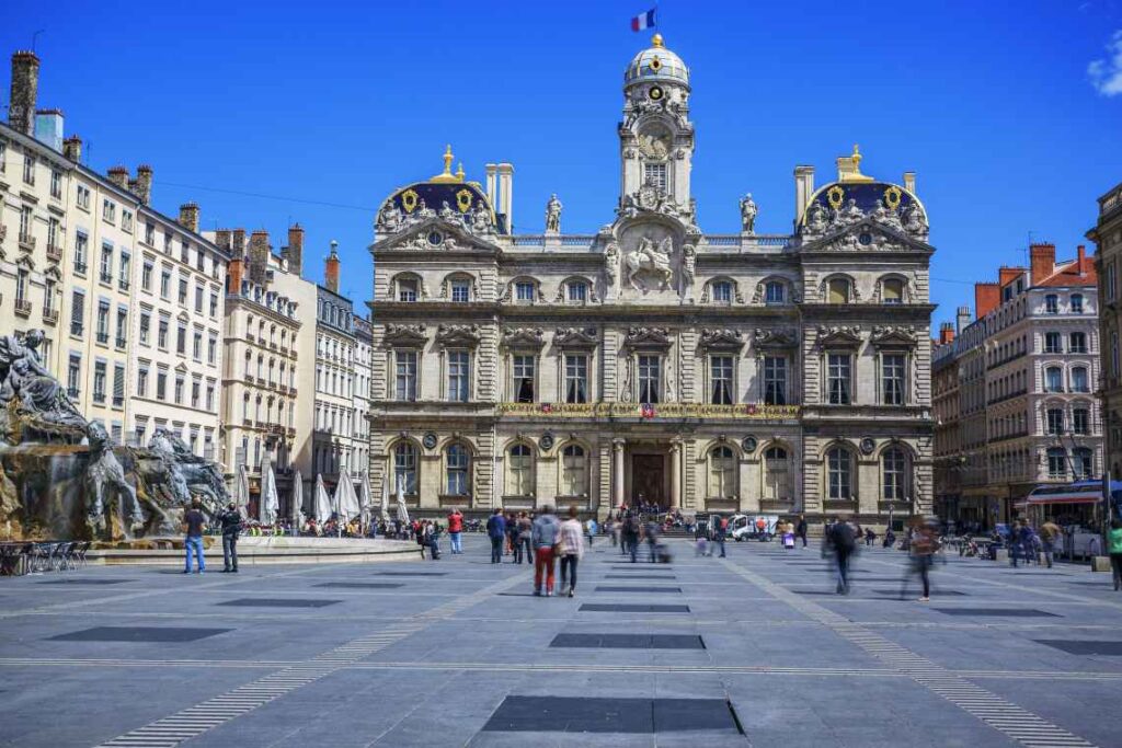 large open square in lyon france with black stones and ornate building in the background