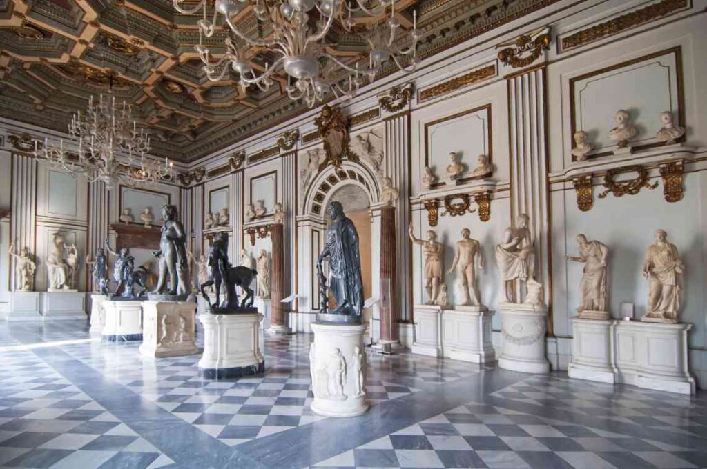 ornate room at a museum in rome with checkered marble floor and stone statues