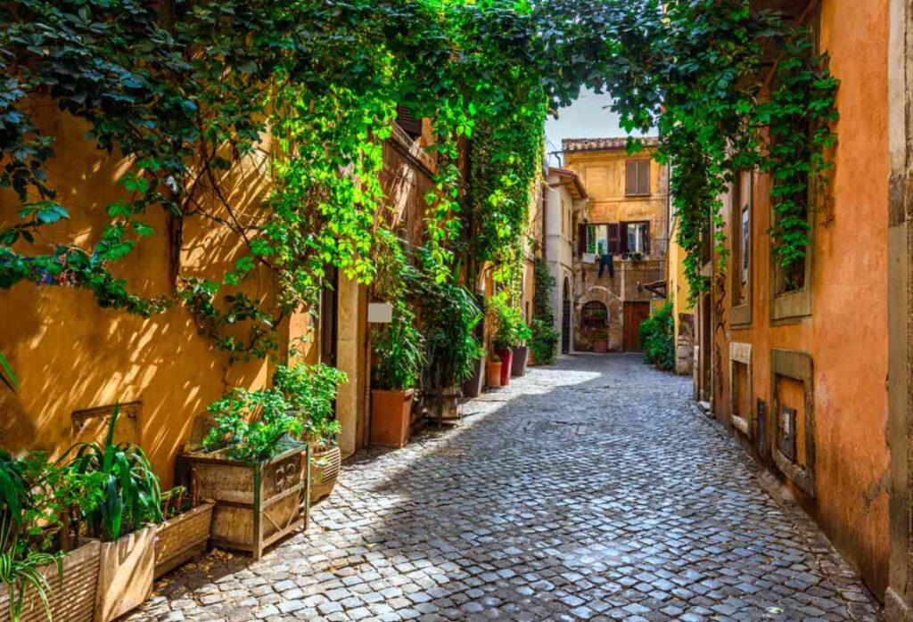 cobblestone walkways and green vine covered terracotta buildings in the trastevere neighborhood of rome