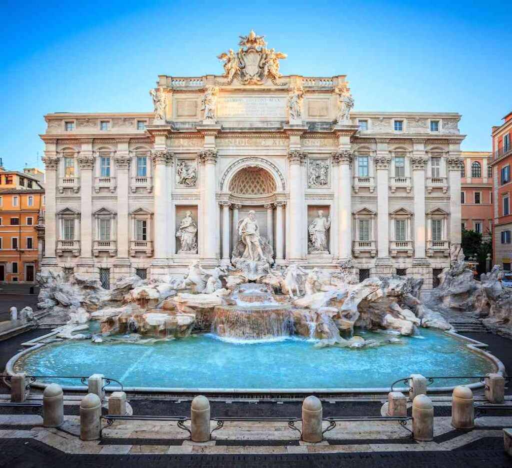 ornate white marble trevi fountain with water flowing in rome