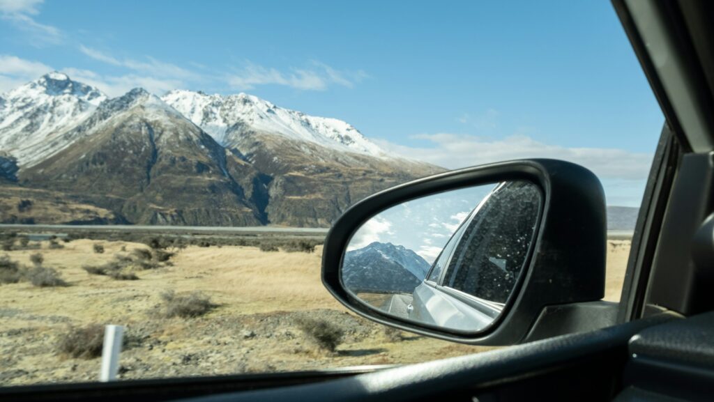 A car's side view mirror with a mountain in the background