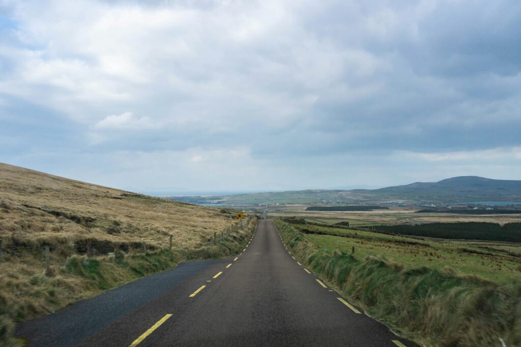 A long empty road with a grassy hill in the background in Ireland