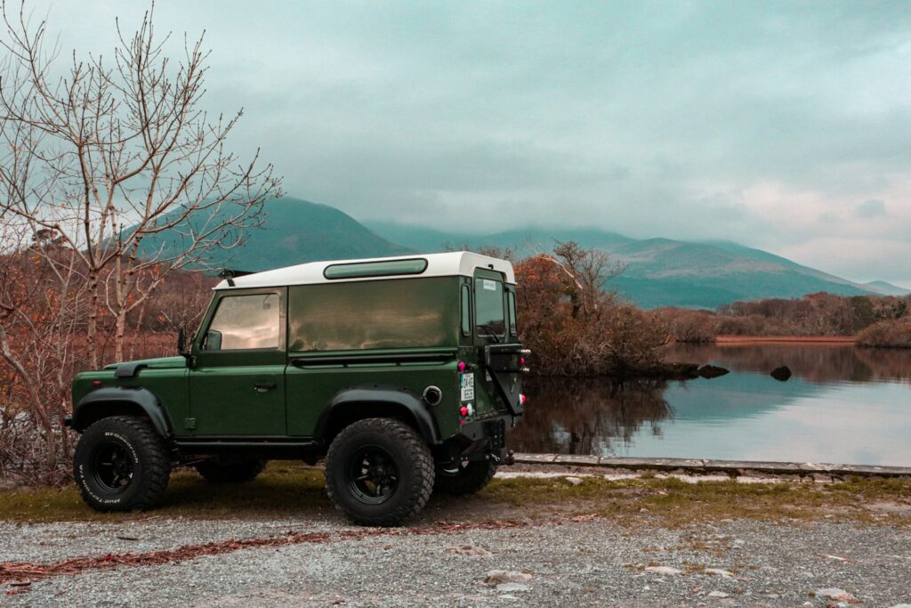 A green and white jeep parked next to a body of water in Killarney