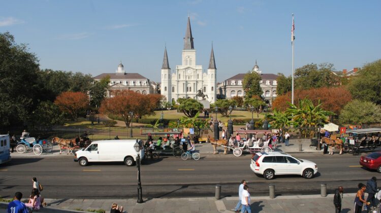 A white sedan on the road near St. Louis Cathedral during the day in New Orleans.