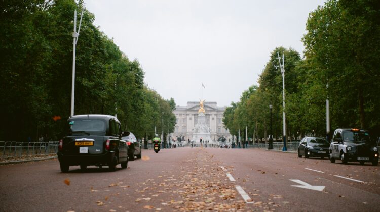 A black car driving down a street next to Buckingham Palace in London.