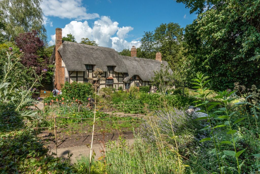 A house with a thatched roof surrounded by trees in Stratford-upon-Avon, Warwickshire.