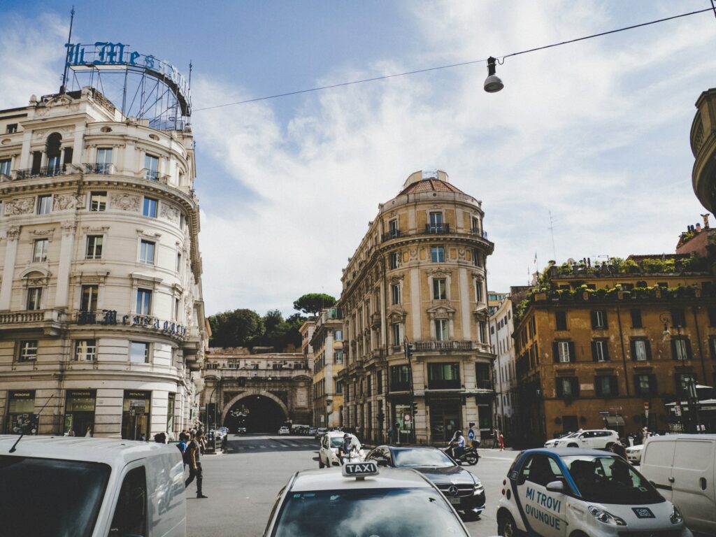 Several cars parked alongside a brown building in Rome, Italy, with urban architecture and city ambiance.
