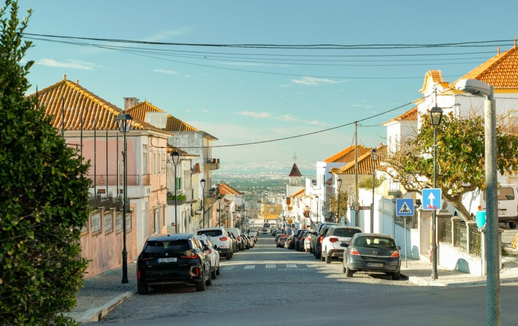 A street with cars parked on both sides of it in Palmela, Portugal.