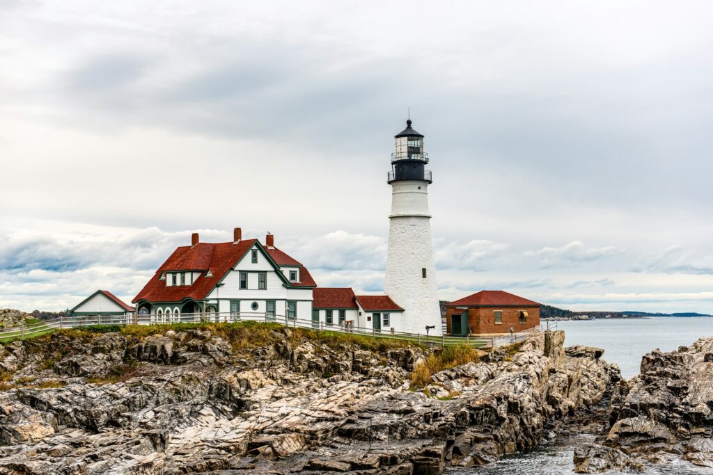 A lighthouse on a rocky shore with a body of water in the background at Portland