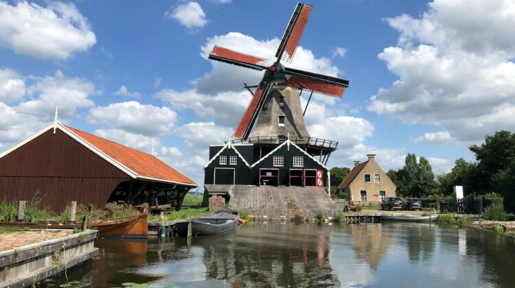 The saw windmill "De Rat" at IJlst, Netherlands, next to a calm body of water surrounded by greenery.