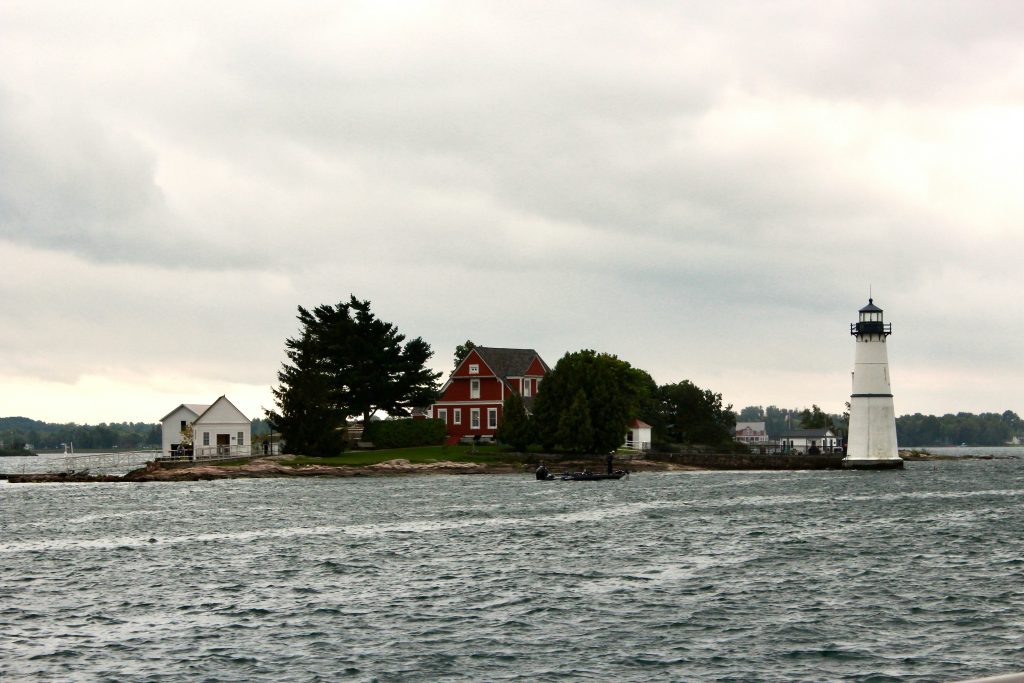A small island with a red house and a white lighthouse, Thousand Islands.