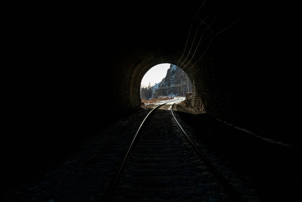 A dark railway tunnel with light visible at the far end.