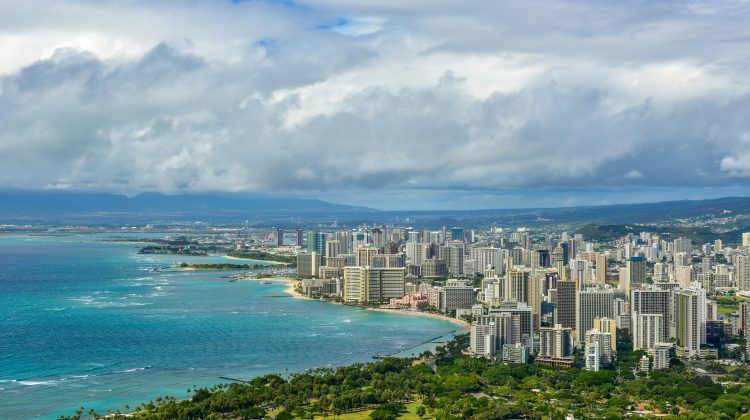 Aerial view of Honolulu's coastline with turquoise waters, Waikiki Beach, and the city skyline.